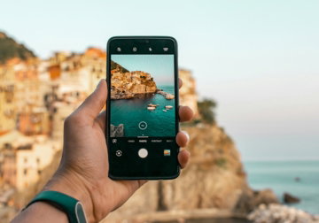 person holding a phone near cliff during daytime